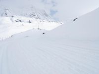 a man riding a snowboard down a snow covered mountain side ski slope in the distance