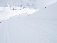 a man riding a snowboard down a snow covered mountain side ski slope in the distance