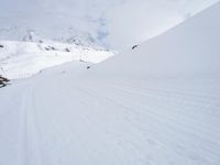 a man riding a snowboard down a snow covered mountain side ski slope in the distance