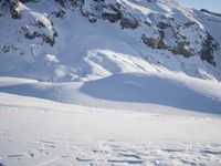 a snowboarder coming down a very snowy hill side trail through some snow capped mountains