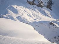a snowboarder coming down a very snowy hill side trail through some snow capped mountains