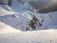 a snowboarder coming down a very snowy hill side trail through some snow capped mountains