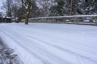 a person snowboarding down the road near a small wooden bridge and some trees on the side of the street