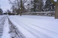 a person snowboarding down the road near a small wooden bridge and some trees on the side of the street