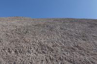 a snow boarder is riding on the rocky shore line, near some sand mountains