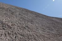 a snow boarder is riding on the rocky shore line, near some sand mountains