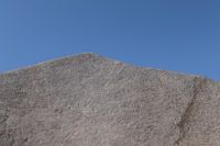 a snow boarder is riding on the rocky shore line, near some sand mountains