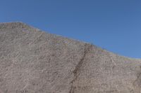 a snow boarder is riding on the rocky shore line, near some sand mountains