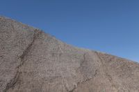 a snow boarder is riding on the rocky shore line, near some sand mountains