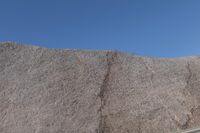 a snow boarder is riding on the rocky shore line, near some sand mountains