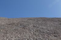 a snow boarder is riding on the rocky shore line, near some sand mountains