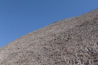 a snow boarder is riding on the rocky shore line, near some sand mountains