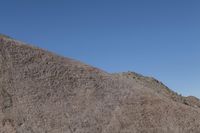 a snow boarder is riding on the rocky shore line, near some sand mountains