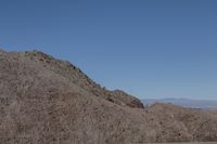 a snow boarder is riding on the rocky shore line, near some sand mountains