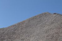 a snow boarder is riding on the rocky shore line, near some sand mountains