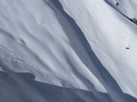 a skier is coming down a steep mountain slope in snows on the other side