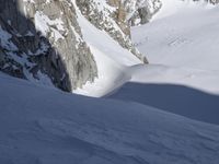 someone is snow skiing down a mountain in the snow near the mountains and a person is climbing