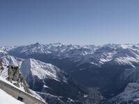 someone standing atop a snowy mountain slope with skis on their feet and in the air