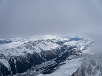 the view from an airplane of a snowy mountain range with clouds and snow capped peaks