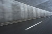 a blurry image of a road in an tunnel with rain, as viewed from the front seat of a car