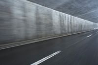 a blurry image of a road in an tunnel with rain, as viewed from the front seat of a car