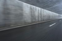 a blurry image of a road in an tunnel with rain, as viewed from the front seat of a car