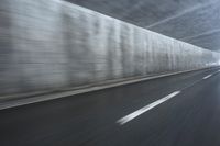 a blurry image of a road in an tunnel with rain, as viewed from the front seat of a car