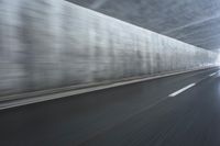 a blurry image of a road in an tunnel with rain, as viewed from the front seat of a car