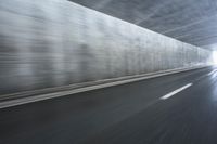 a blurry image of a road in an tunnel with rain, as viewed from the front seat of a car