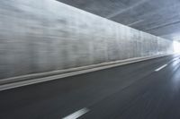 a blurry image of a road in an tunnel with rain, as viewed from the front seat of a car