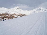 the view over a snowy mountain town and ski tracks are visible on the ski slope