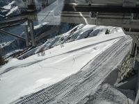 the view from a cable car of a snow covered slope and tracks in the snow