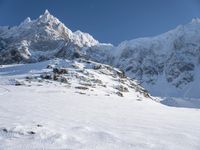 a man on skis stands on the snowy slope at the foot of the mountain