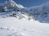 a man on skis stands on the snowy slope at the foot of the mountain