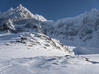 a man on skis stands on the snowy slope at the foot of the mountain