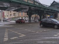 cars passing under a bridge in a city on a snowy day to see it snowing