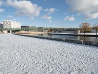 a snow covered field with the bridge in the background and a building on the other side