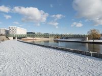 a snow covered field with the bridge in the background and a building on the other side