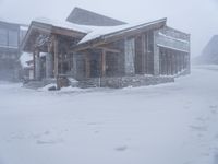 the big cabin is sitting in front of a big building of snow and snow flakes