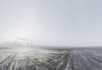 an airport with snow on the ground and city in background on an overcast day