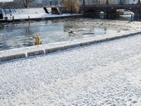 an icy waterway in the center of a snowy city yard with two people walking and walking around