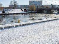 an icy waterway in the center of a snowy city yard with two people walking and walking around