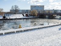 an icy waterway in the center of a snowy city yard with two people walking and walking around