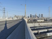 power lines above a cityscape with a railway bridge in the background on a clear, autumn day