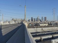 power lines above a cityscape with a railway bridge in the background on a clear, autumn day