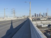 power lines above a cityscape with a railway bridge in the background on a clear, autumn day