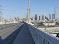 power lines above a cityscape with a railway bridge in the background on a clear, autumn day