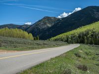 the road is paved with yellow markings and has a snowy mountain range in the background