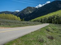 the road is paved with yellow markings and has a snowy mountain range in the background