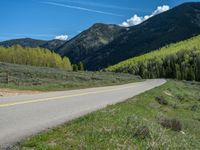 the road is paved with yellow markings and has a snowy mountain range in the background